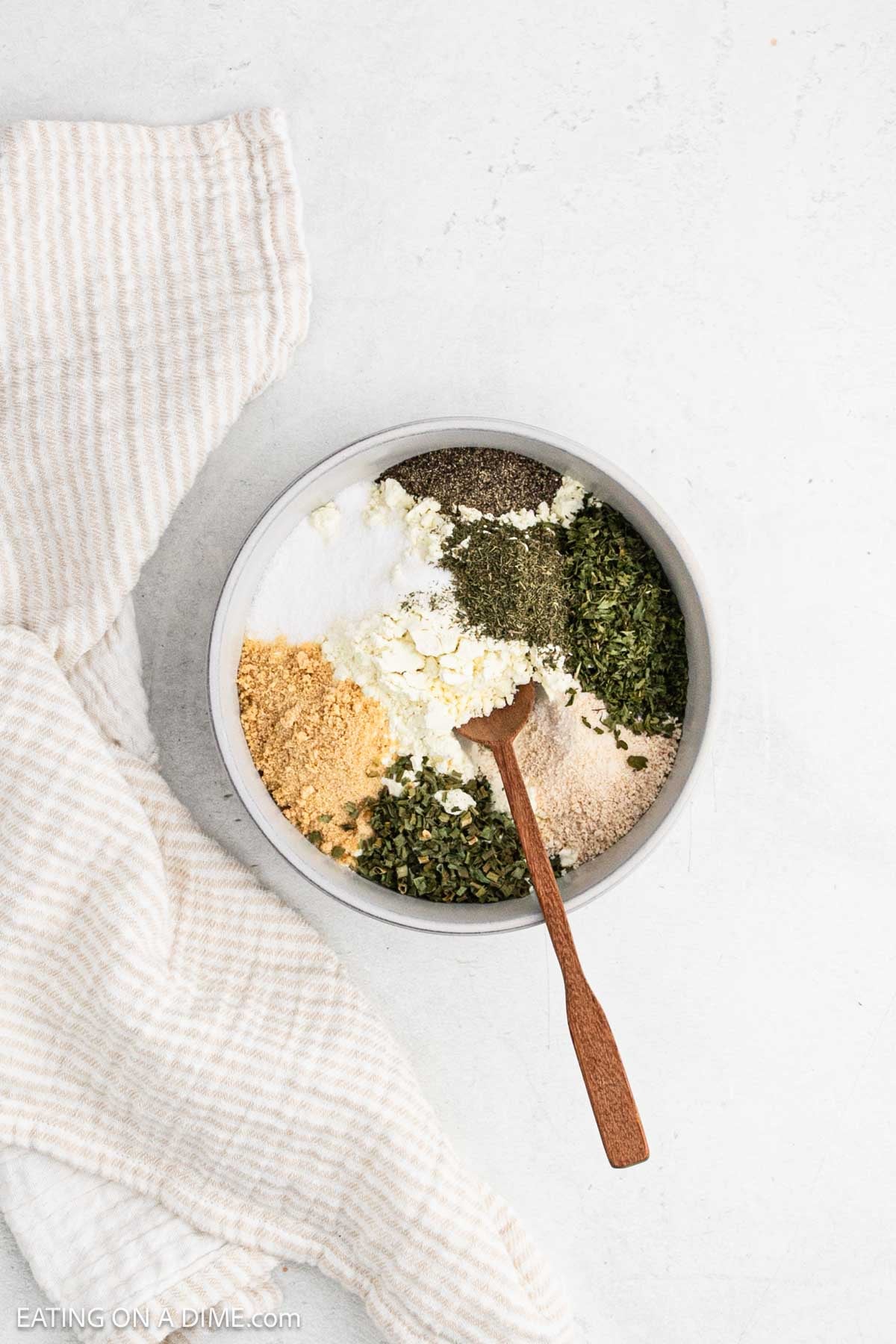 Adding the spices in a bowl with a wooden spoon.