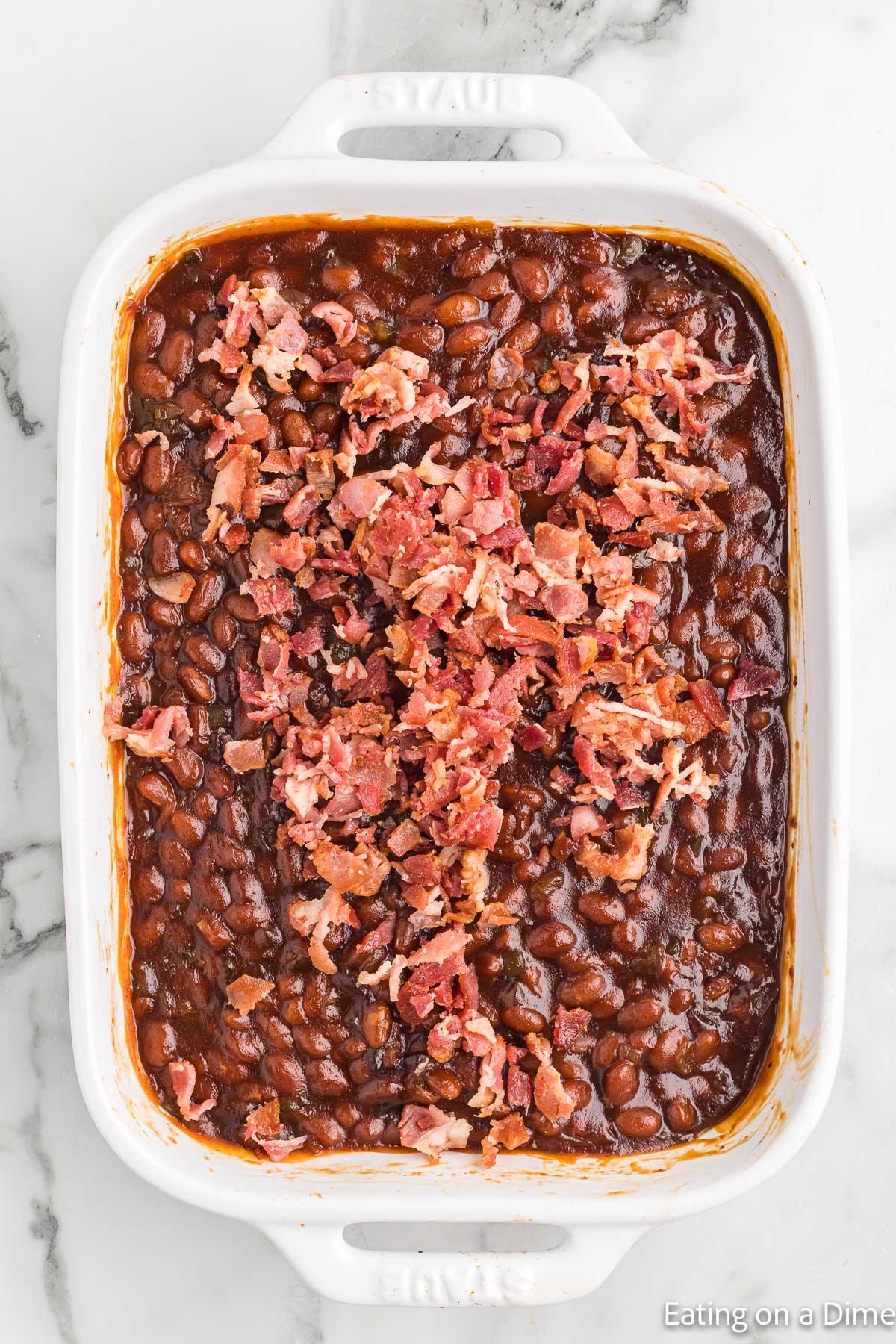 Baked beans in a casserole dish topped with chopped bacon