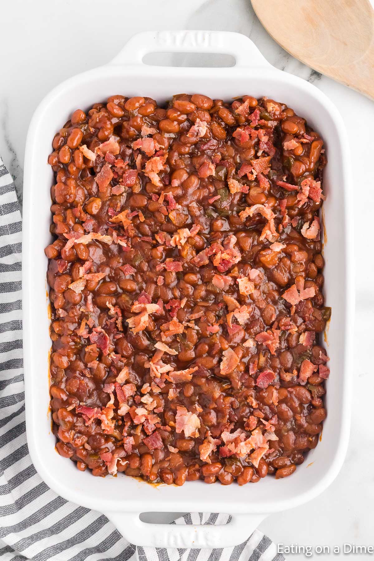 Baked beans in a casserole dish topped with chopped bacon