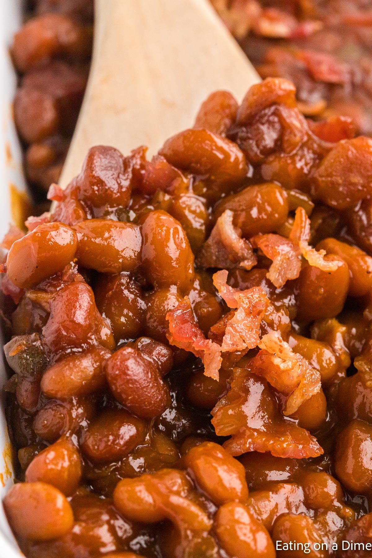 Close up image of baked beans in a wooden spoon