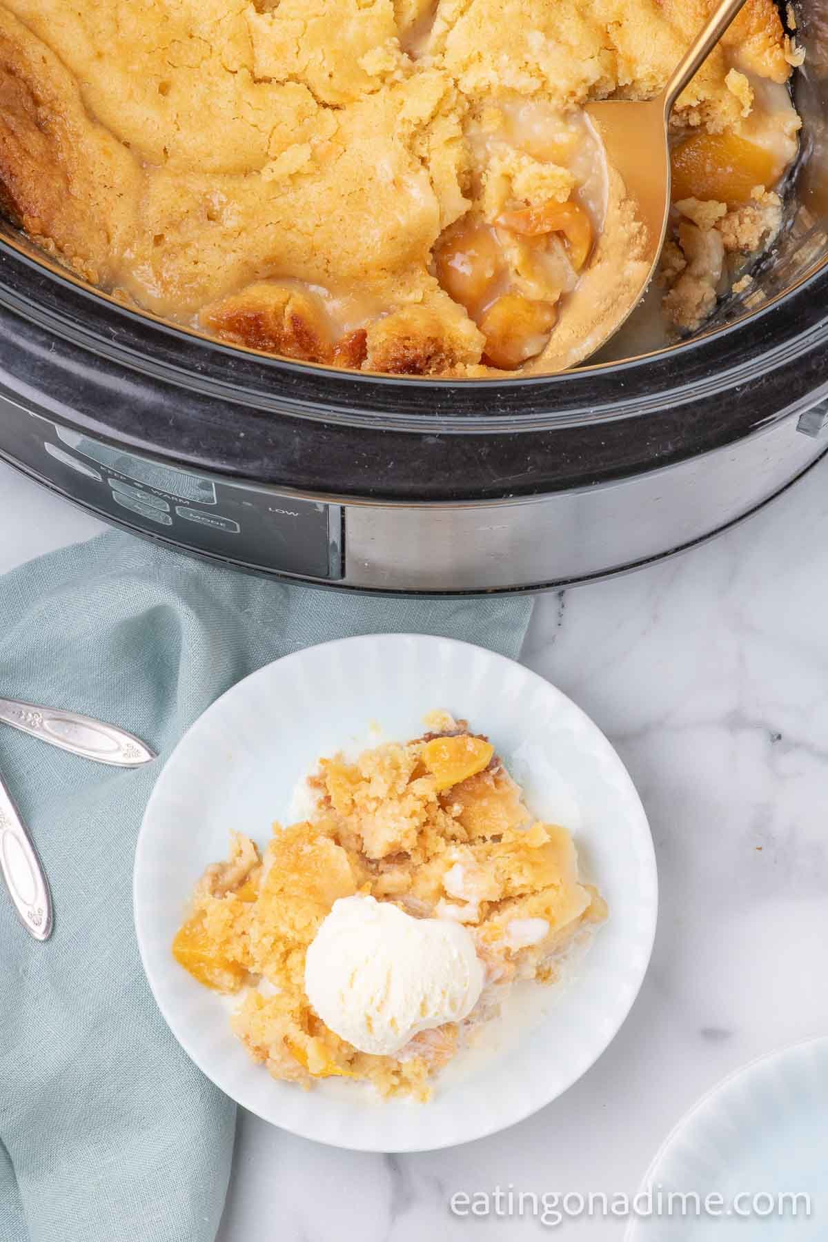 Slow cooker peach cobbler with a serving on a plate