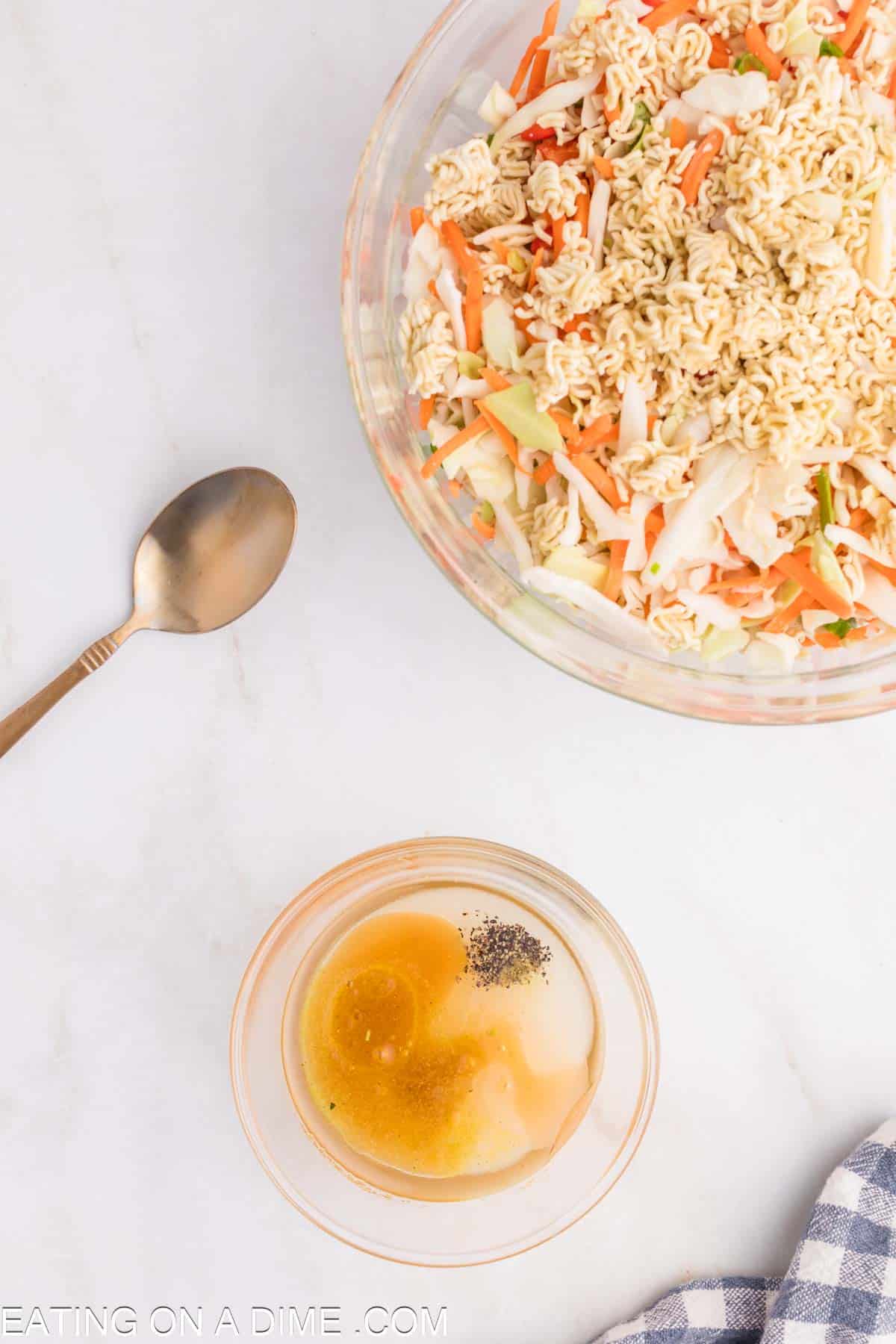 Mixing the oil based dressing in a bowl and topping the vegetables with noodles