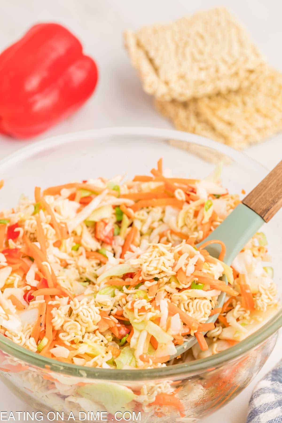 Mixing the ramen noodle salad ingredients in a bowl with a spoon