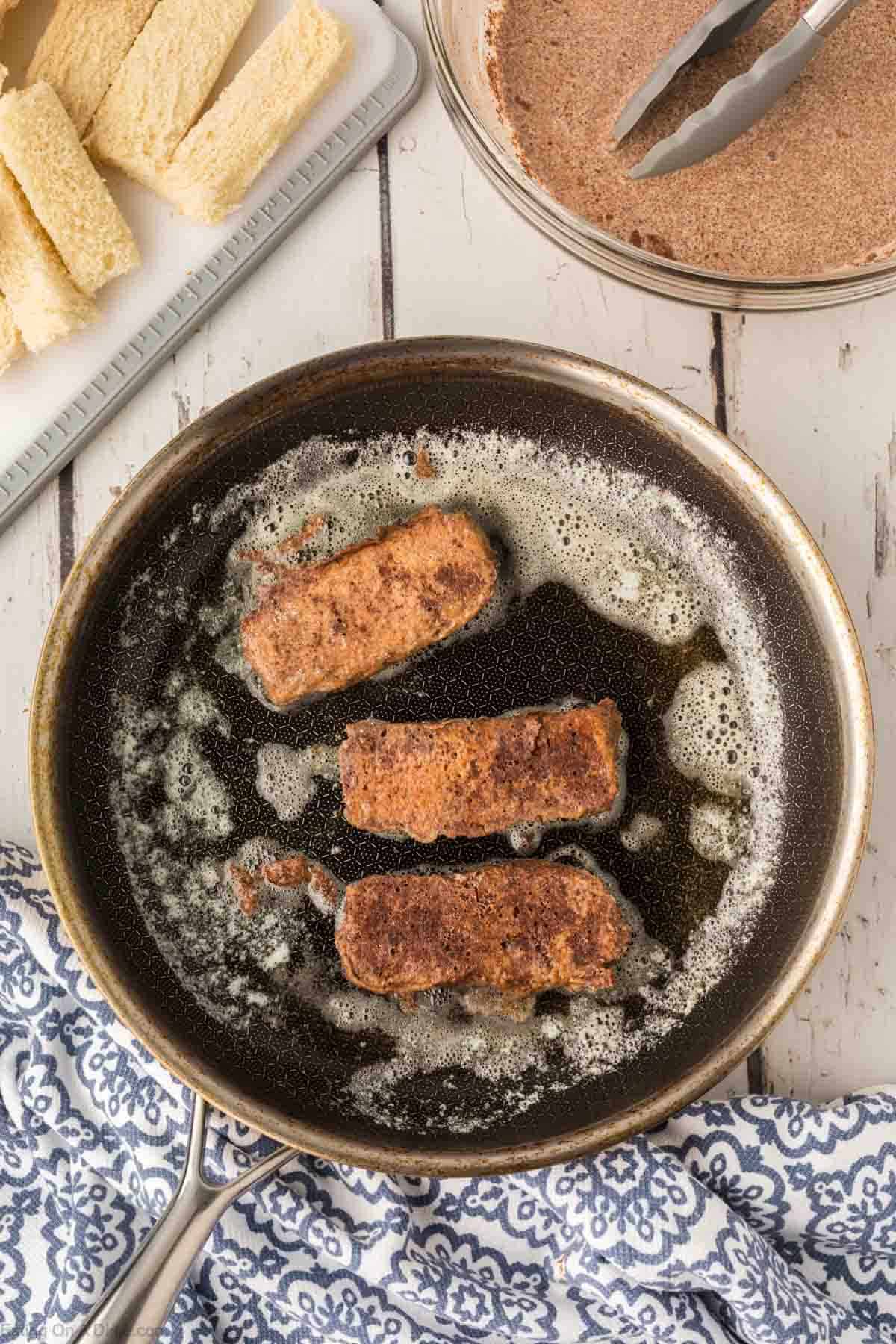 Flipping the French Toast Sticks in a skillet