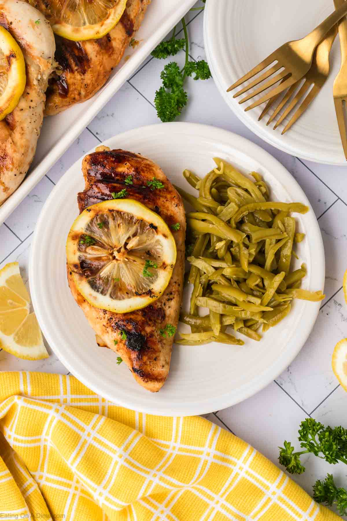 Chicken breast on a plate topped with slice lemon and green beans