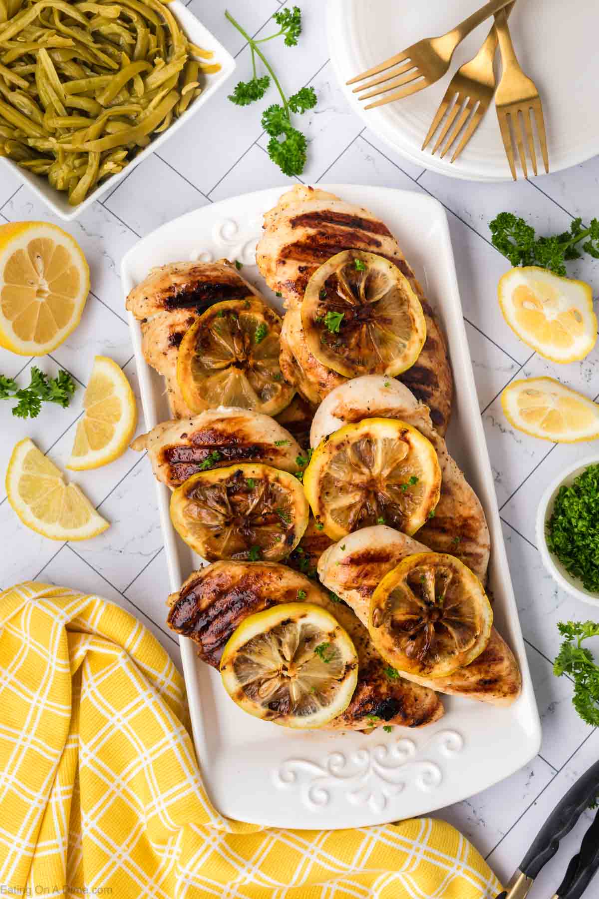 Grilled Chicken stacked on a platter topped with fresh lemon slices