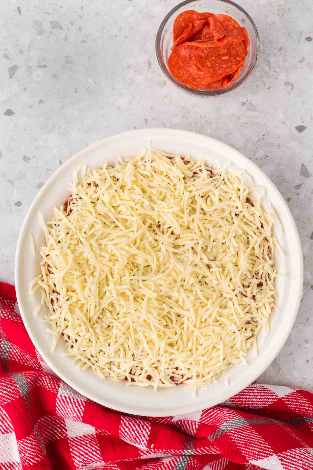 Topping with shredded cheese and pizza sauce