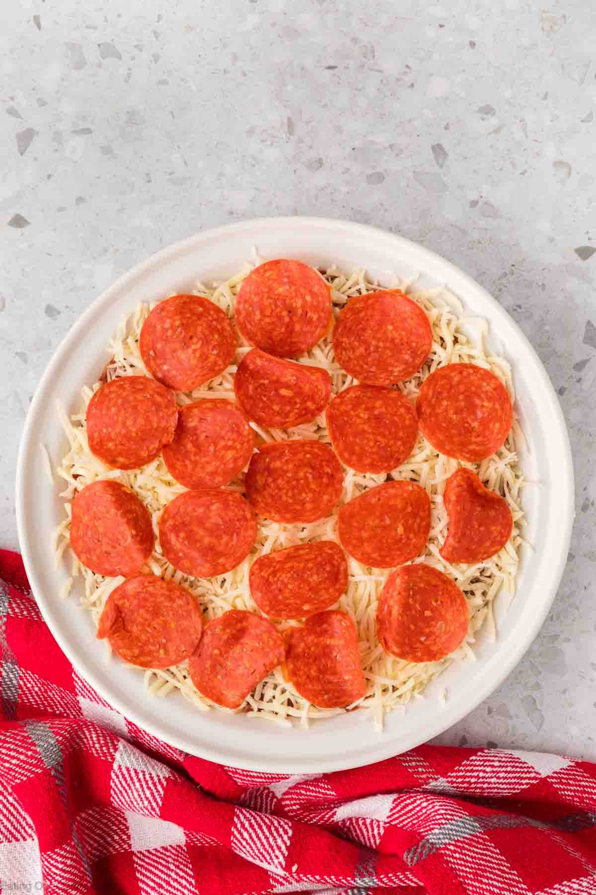 Topping shredded cheese with slices of pepperoni