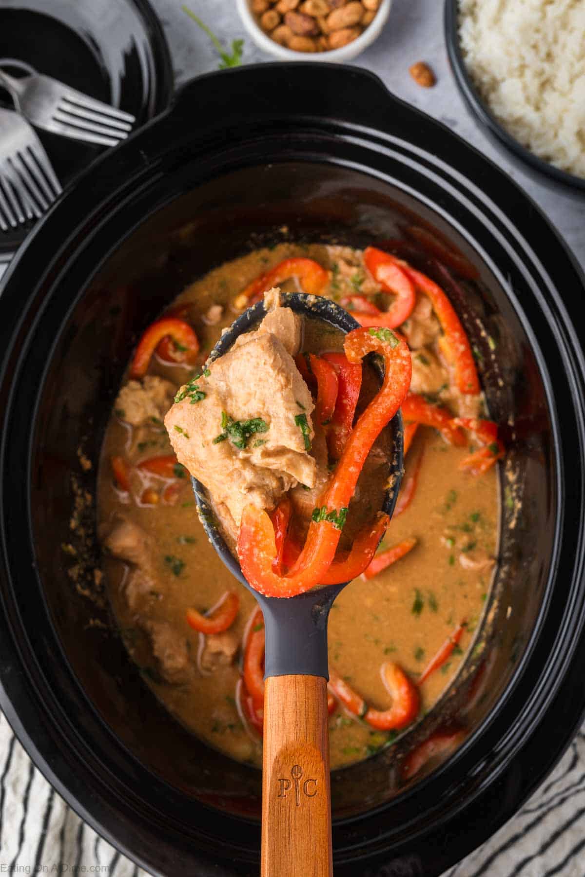 Cooked Thai Peanut Chicken in the slow cooker with a serving on the spoon