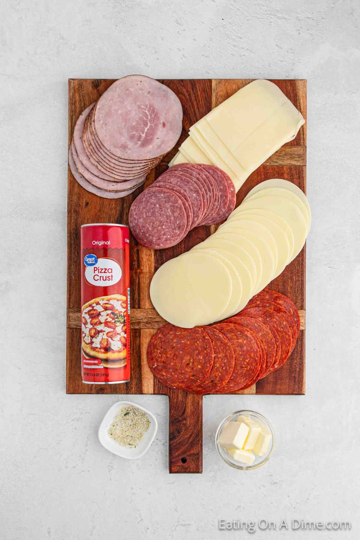 Stromboli ingredients - dough, butter, garlic salt, provolone cheese, ham, pepperoni, salami, mozzarella cheese, sauce