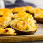 Baked potatoes with cheese and bacon on a baking sheet.