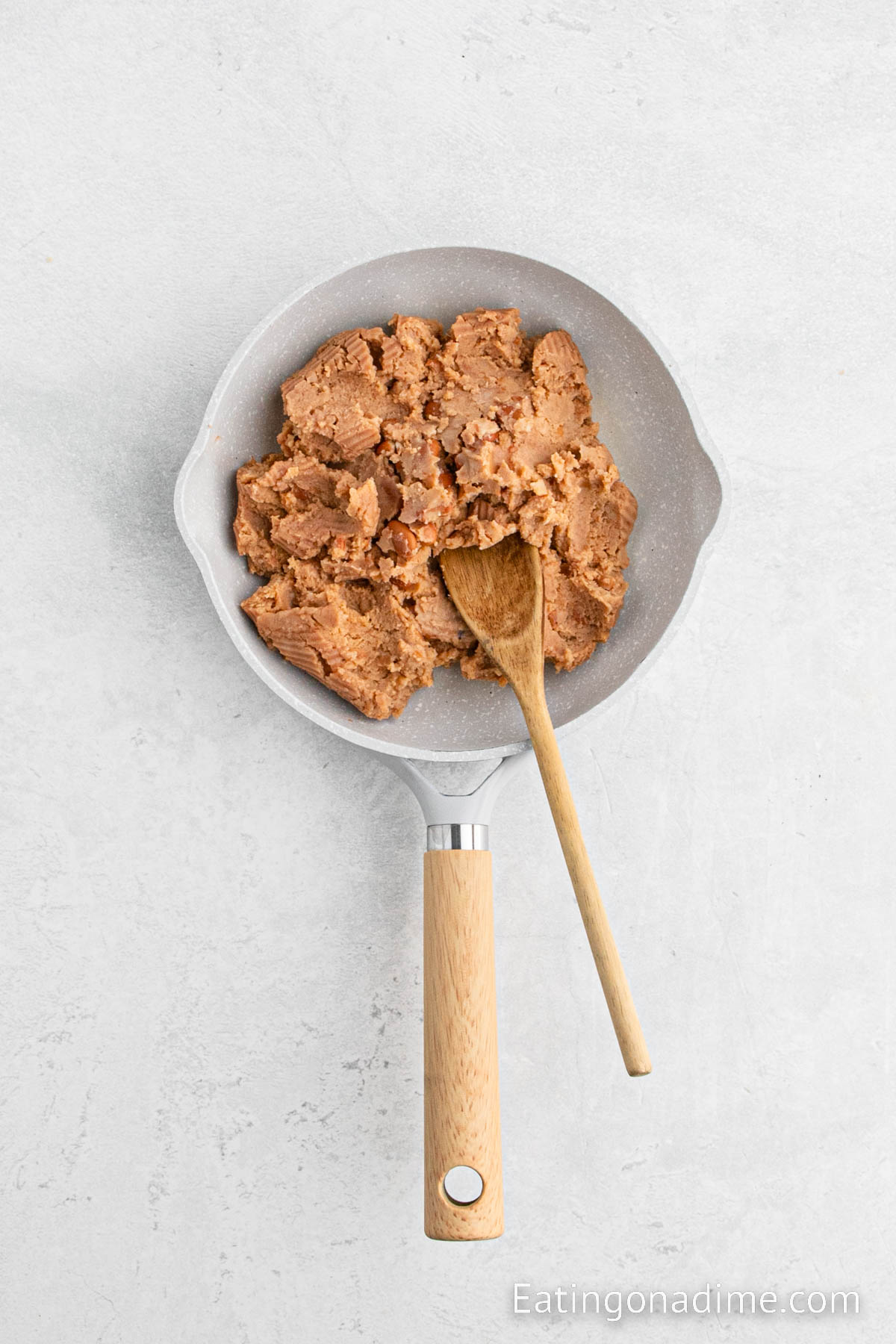 Heating the refried beans in a skillet with a wooden spoon