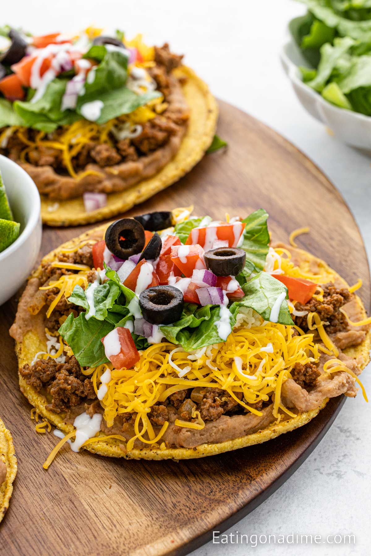 Ground Beef Tostadas topped with cheese, tomatoes, lettuce, black olives