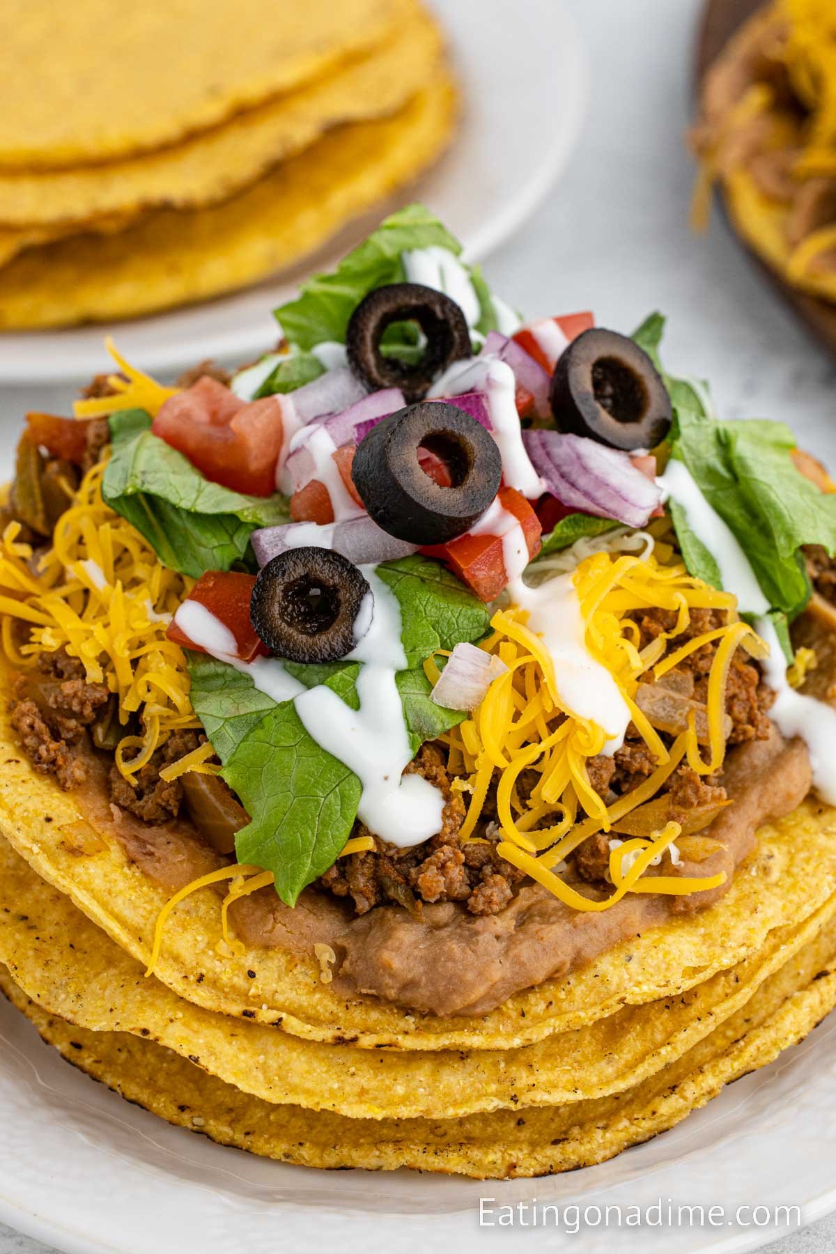 Ground Beef Tostadas topped with refried beans, beef, cheese, lettuce and black olives