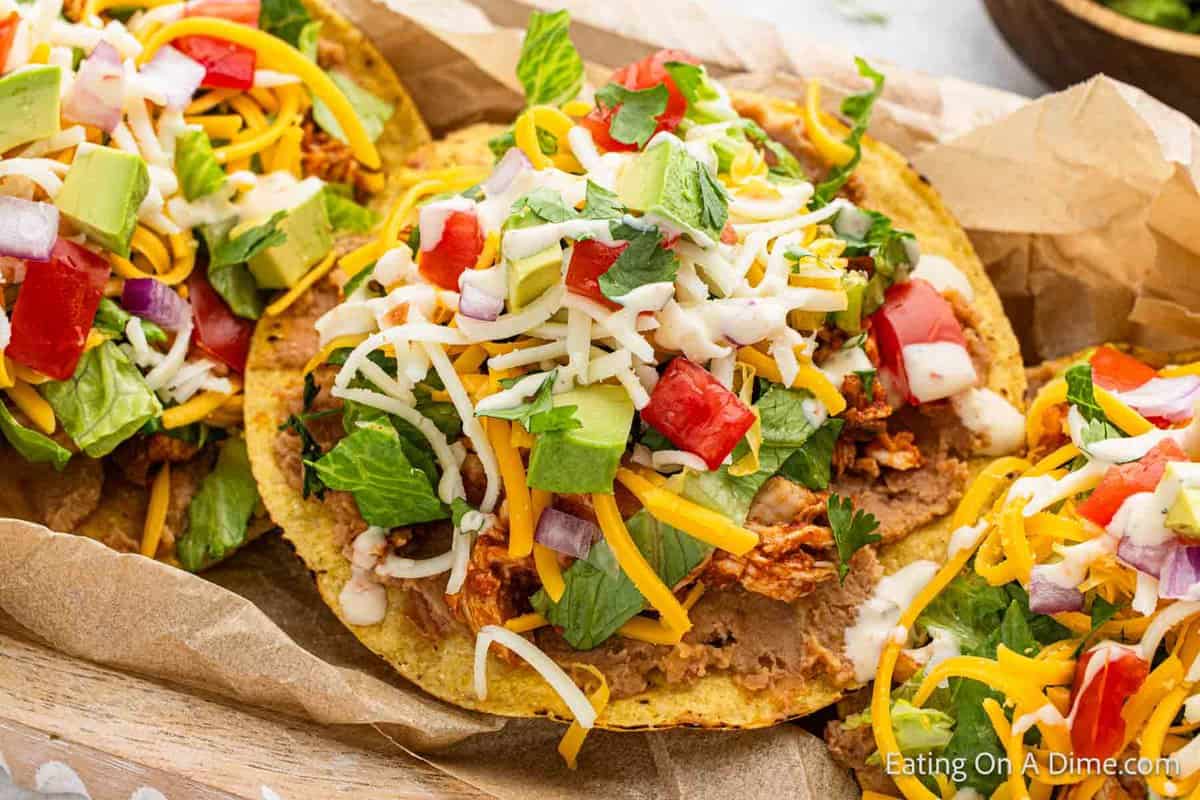 Chicken Tostados arranged together and topped with cheese, onion and lettuce.