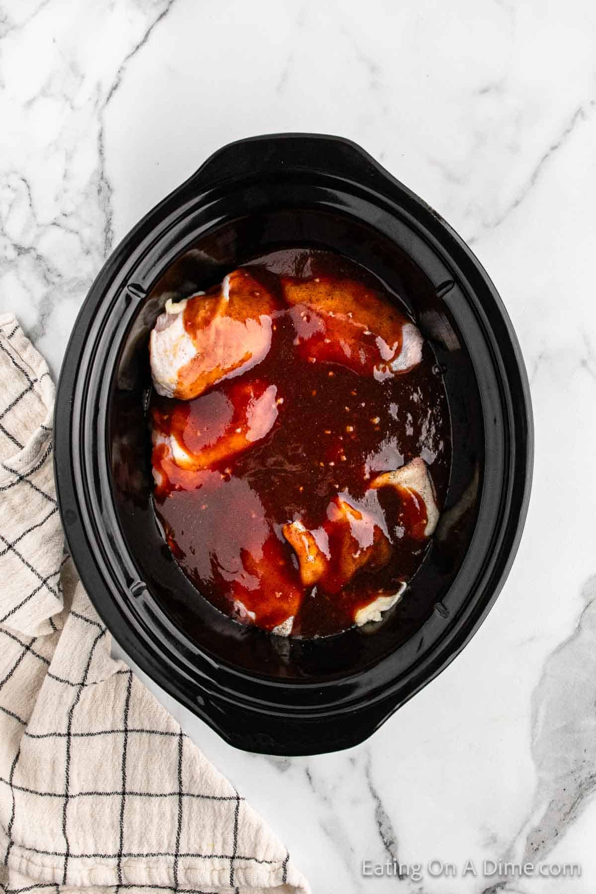 Topping the sauce with the chicken thighs in the slow cooker