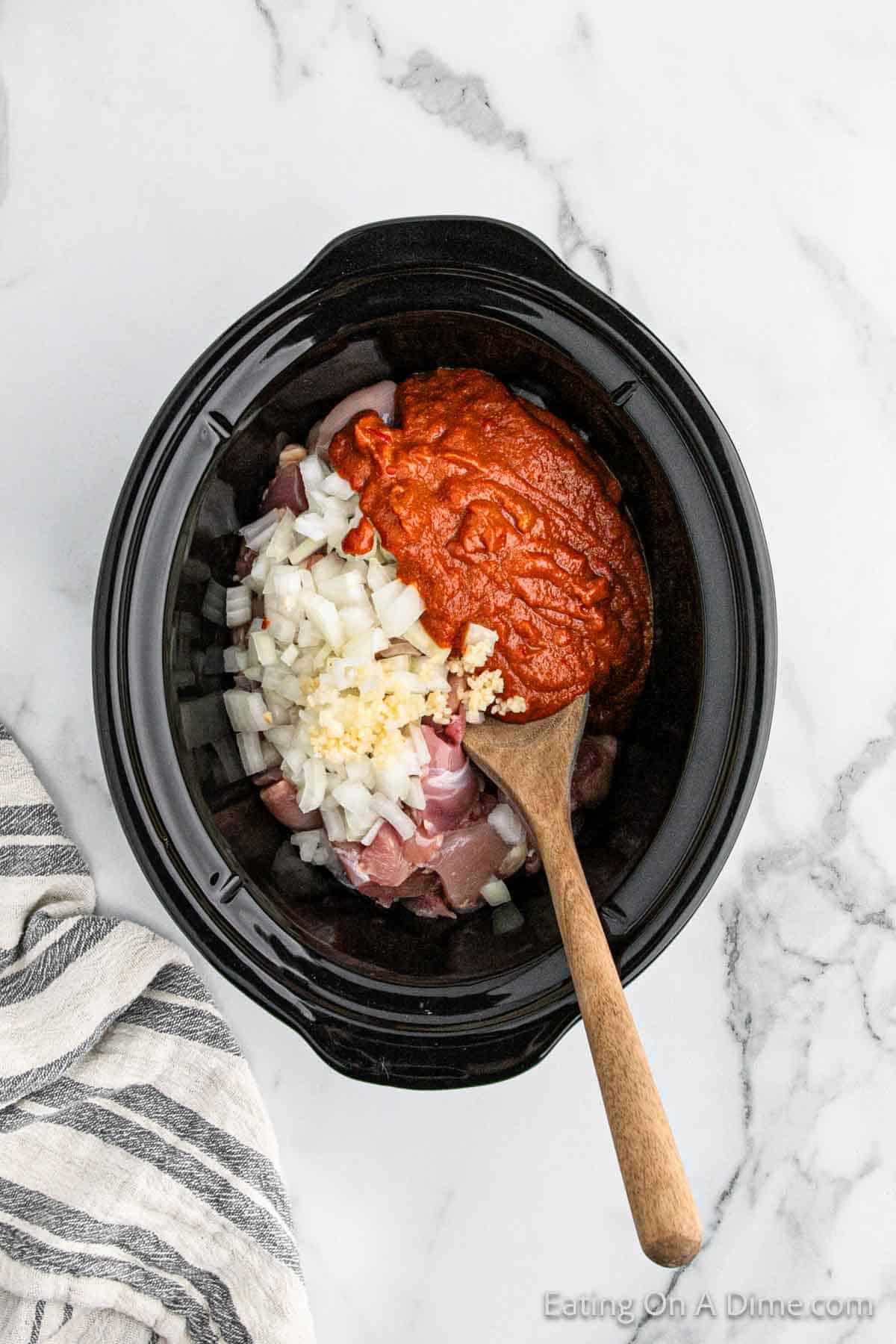 Placing chicken in the slow cooker and topped with the sauce ingredients