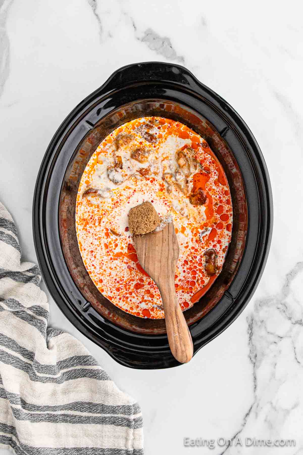 Pouring the heavy cream into the cooked butter chicken in the slow cooker