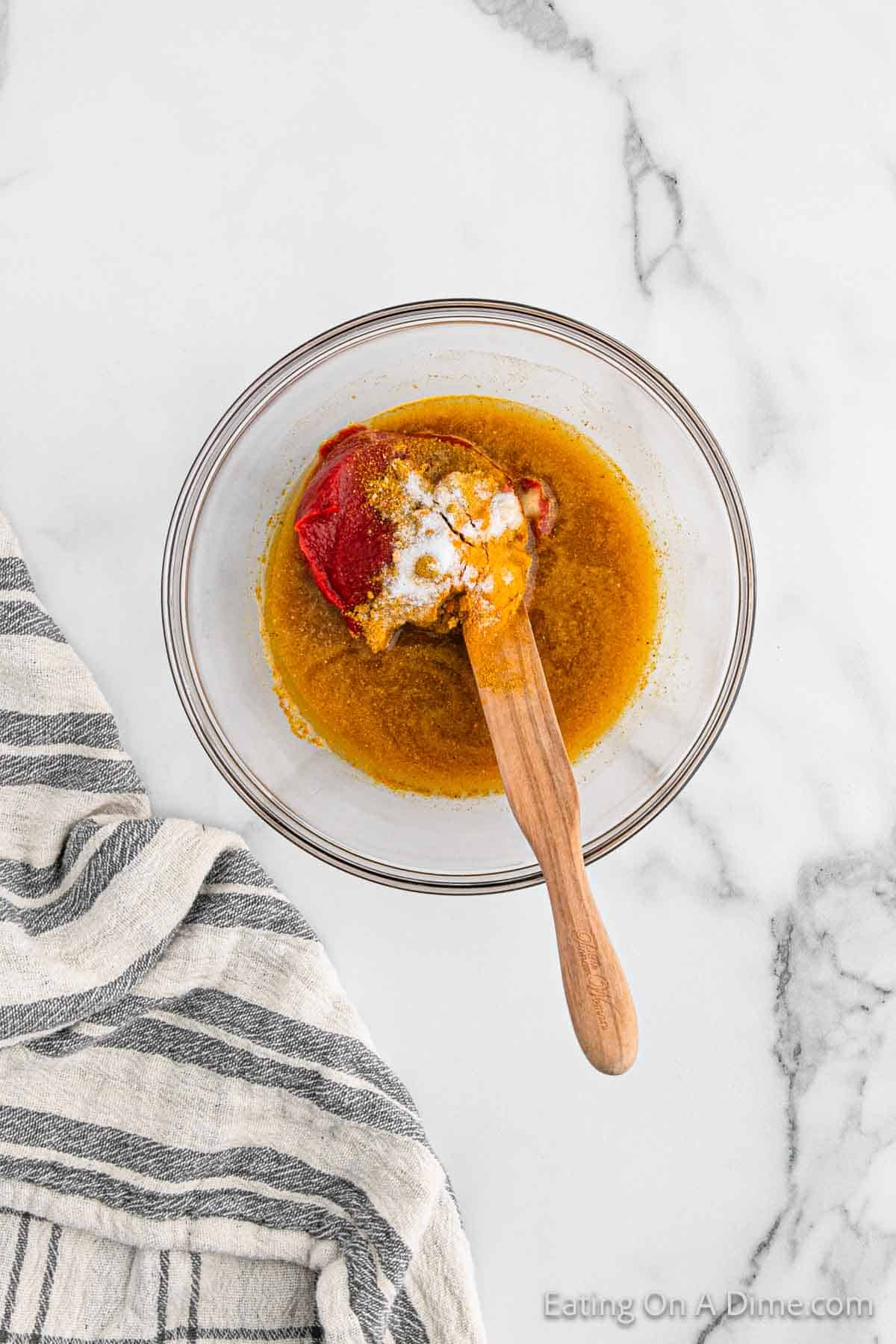 Combining the sauce in a bowl with a wooden spoon