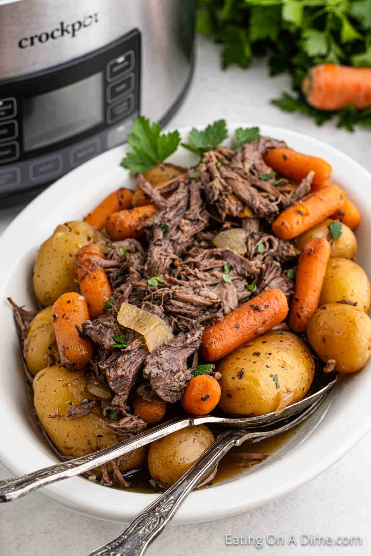 Shredded pot roast on a platter with potatoes and carrots