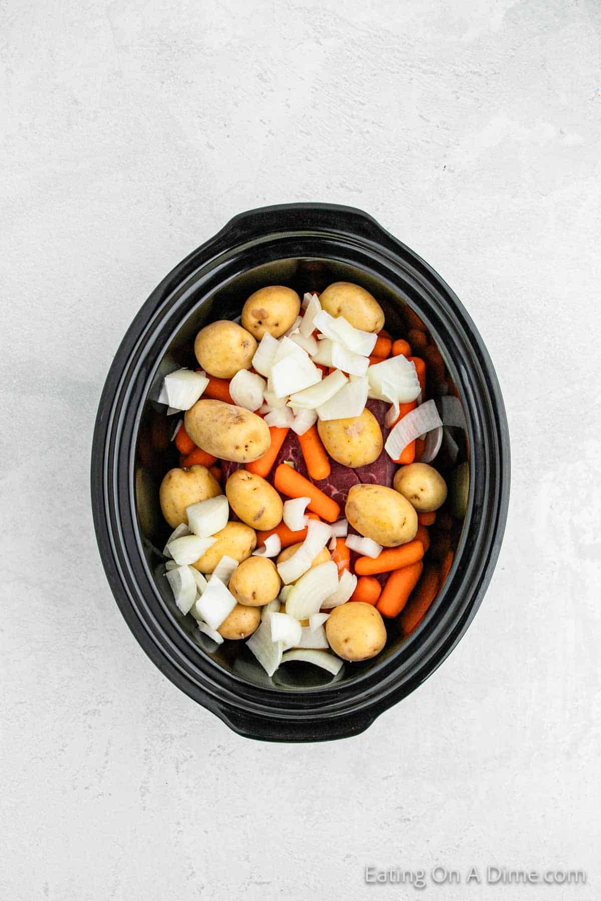 Placing roast, carrots, onions and potatoes in the crock pot
