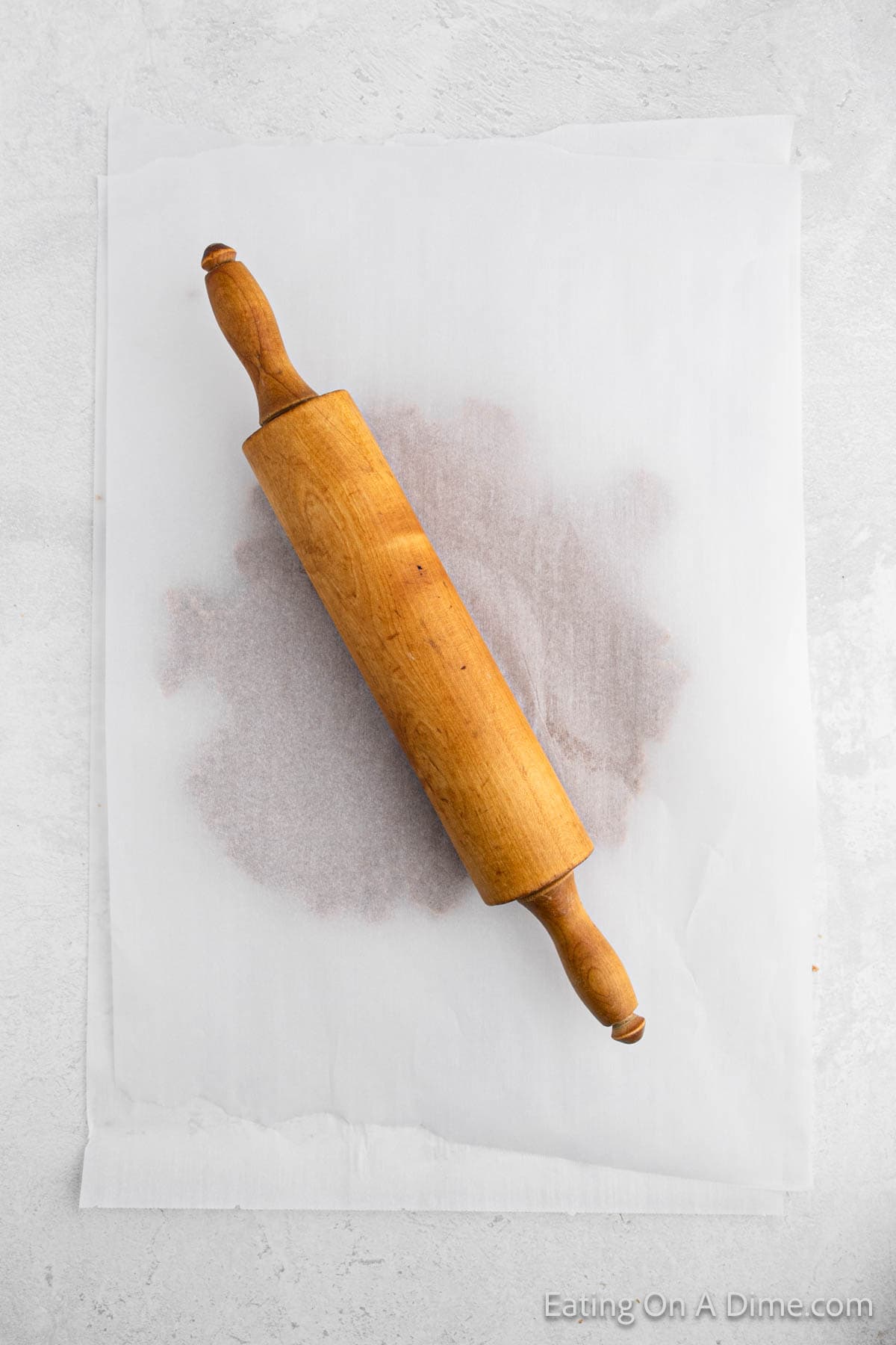 Rolling the dough out with a rolling pin inbetween parchment paper. 