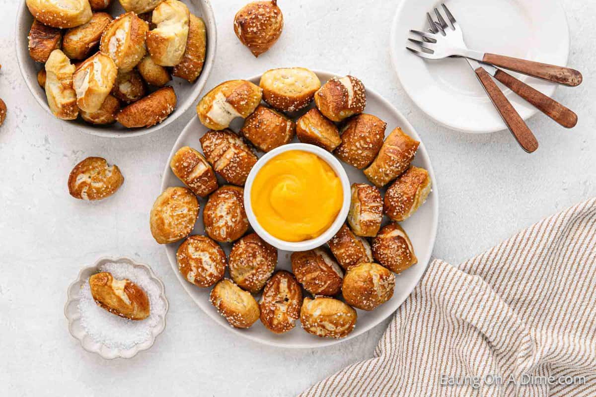Pretzel bites on a white plate with a bowl of cheese 