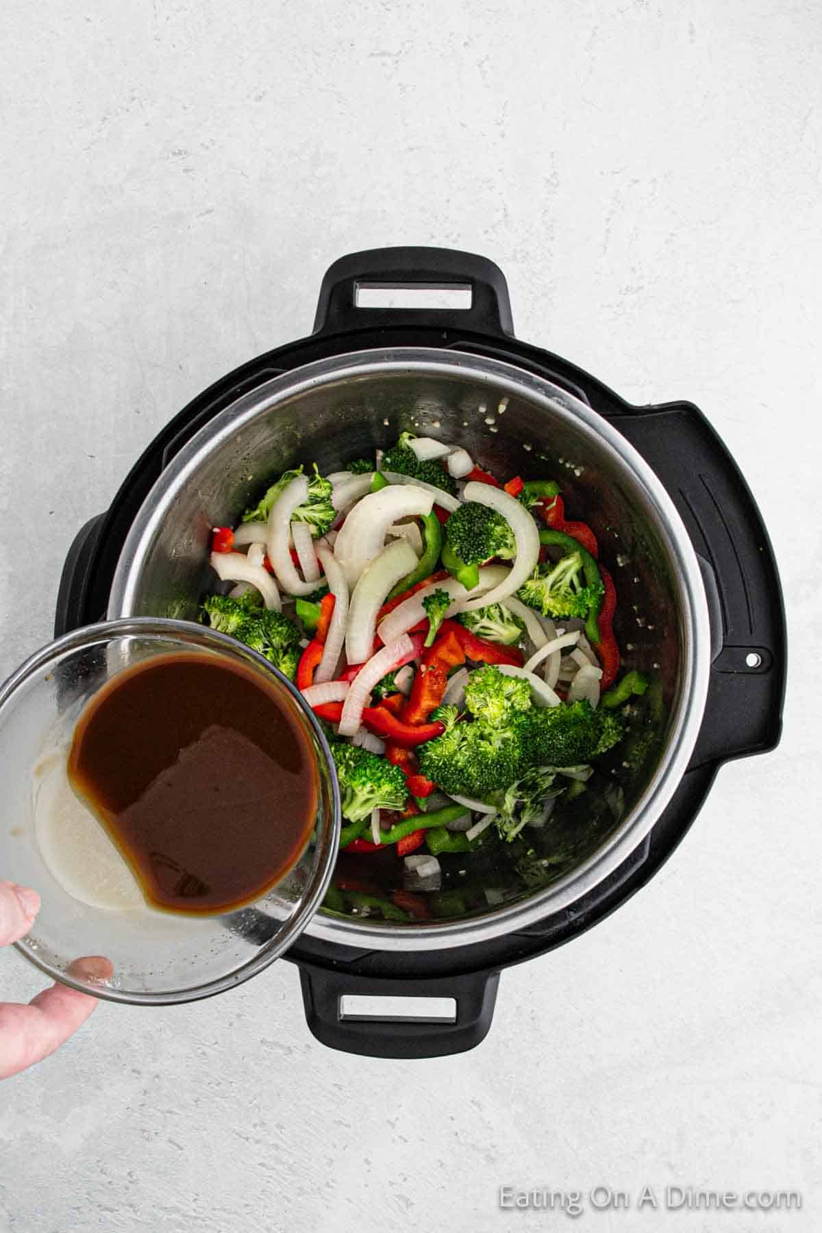 Pouring in the soy sauce mixture in the instant pot with vegetables