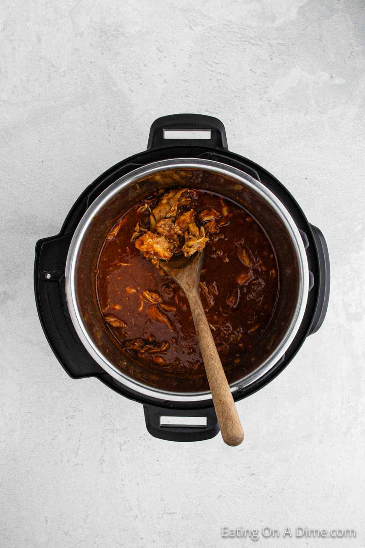 Cooking chicken tikka masala in the instant pot with a wooden spoon
