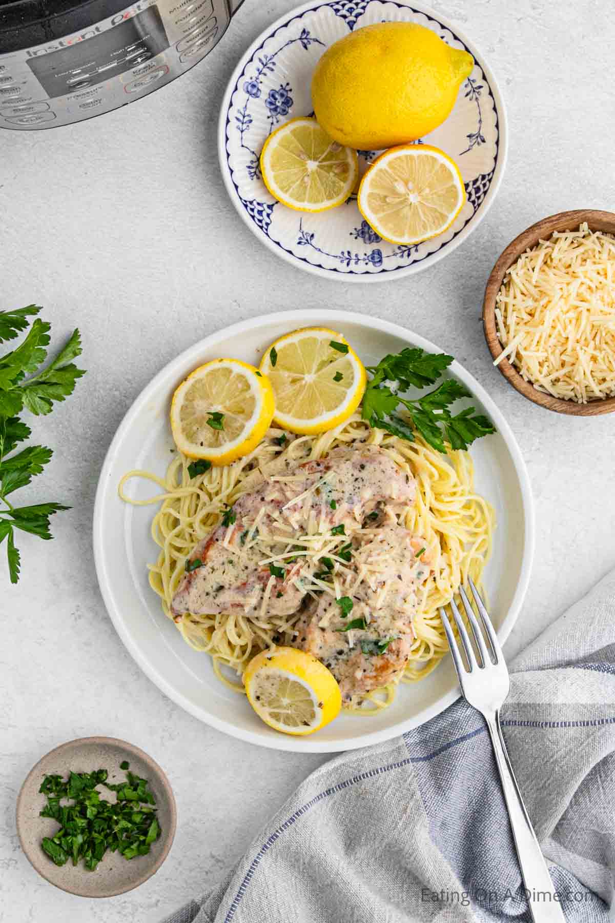 Lemon chicken on a plate with spaghetti and fresh lemons