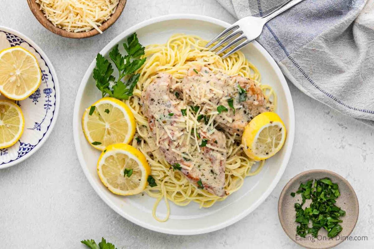 Lemon chicken on a plate with spaghetti and fresh lemons