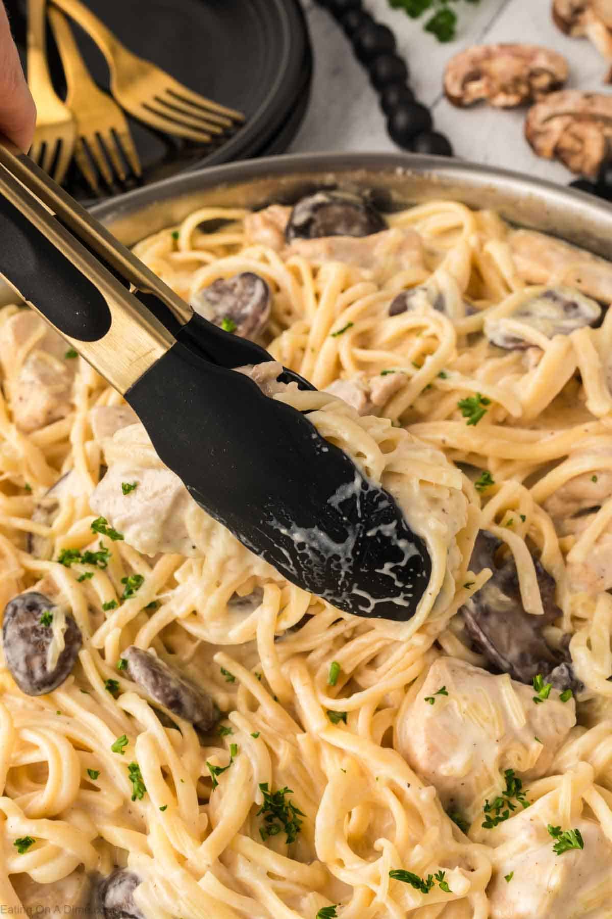 Close up image of chicken tetrazzini in a skillet with a serving on tongs