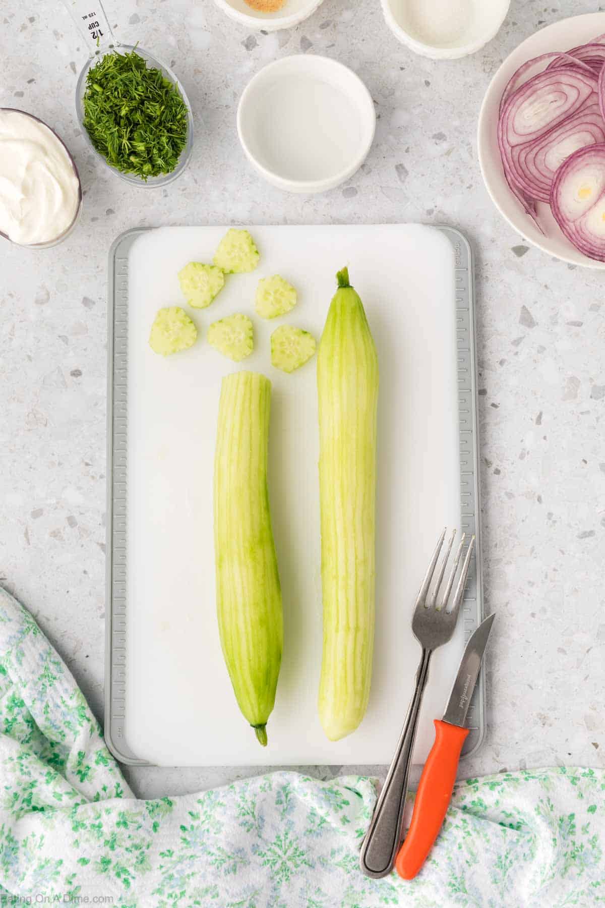 Peeling the cucumber and placing on a cutting board 