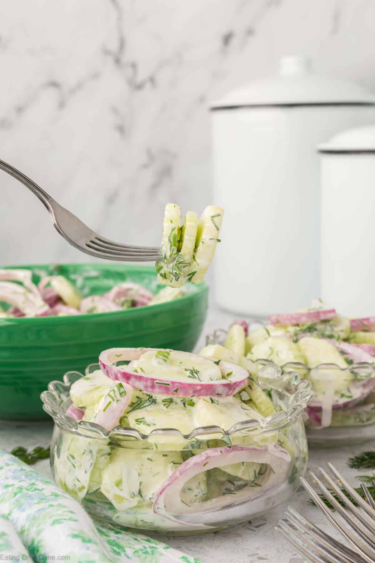 Creamy cucumber salad in a bowl with a bite on a fork