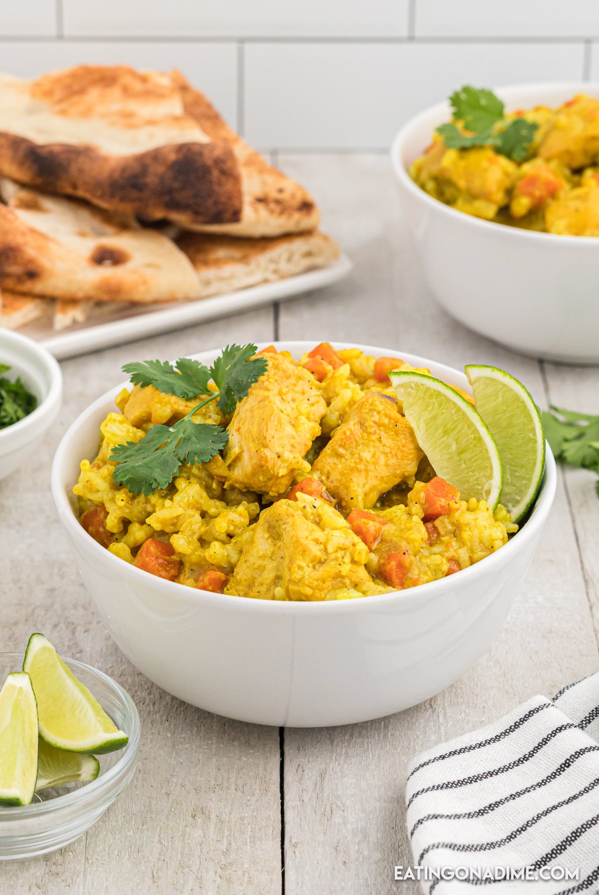 Close up image of chicken curry with rice and a lime in a white bowl. 