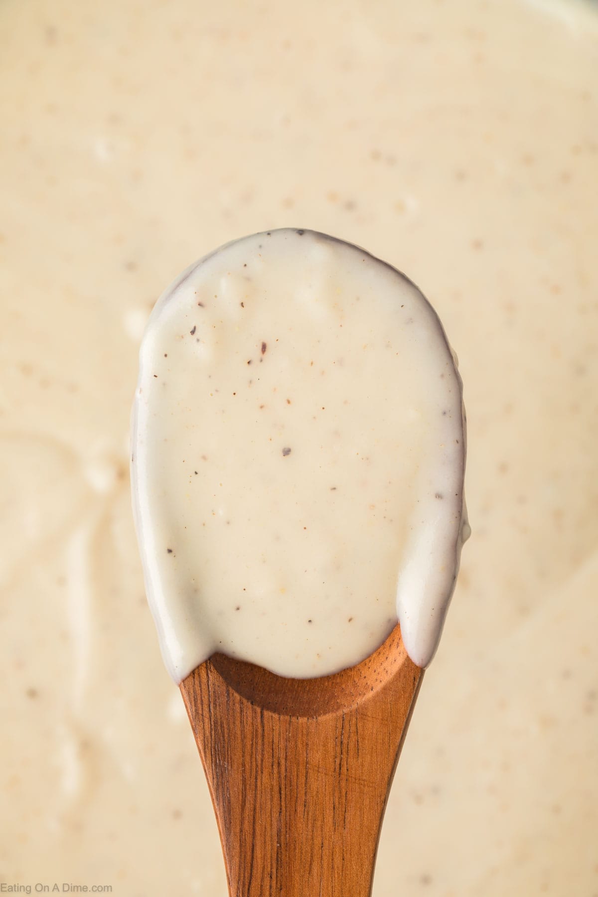 Close up image of white gravy on a wooden spoon