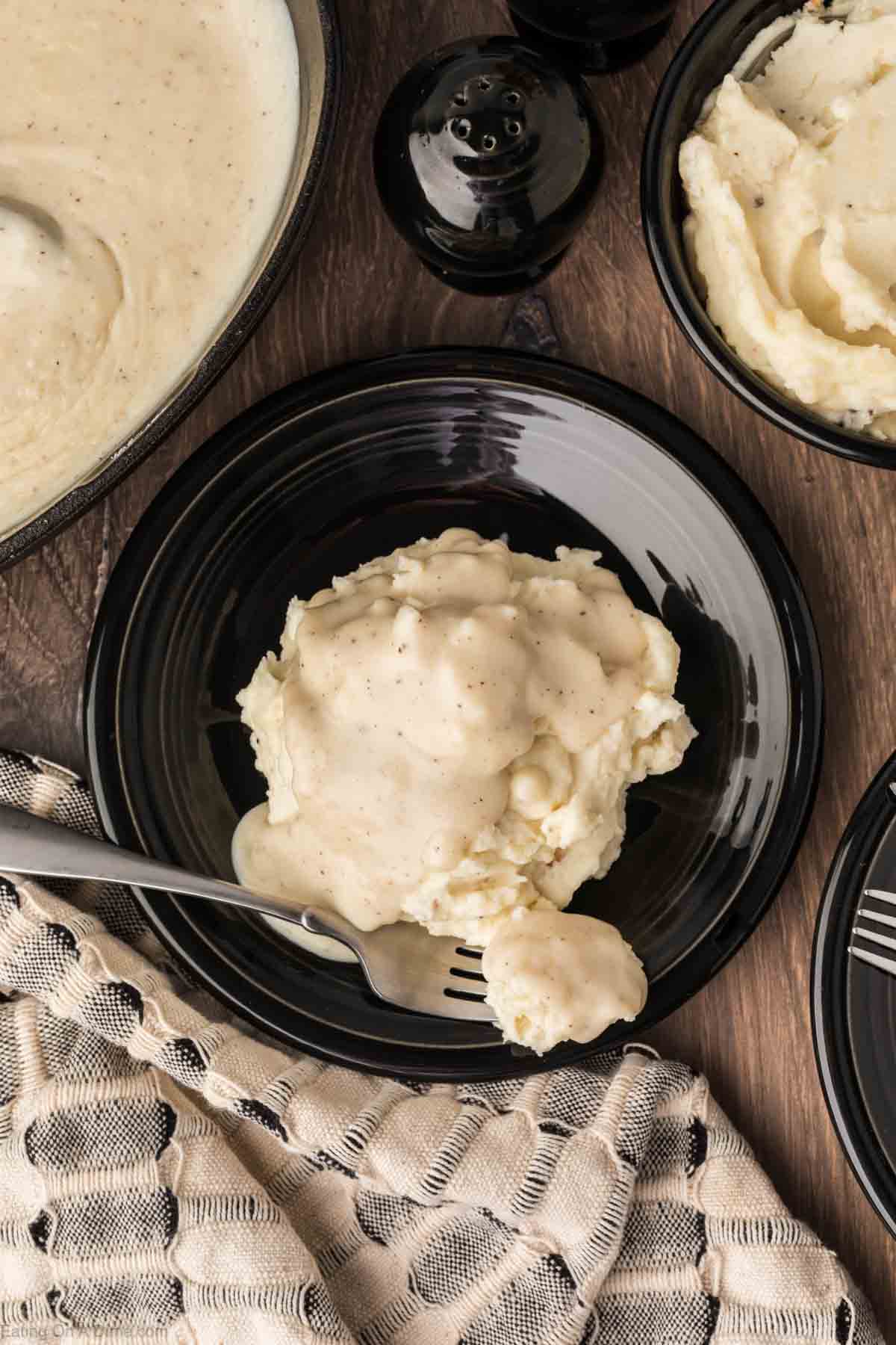 White gravy topped with mashed potatoes on a black plate