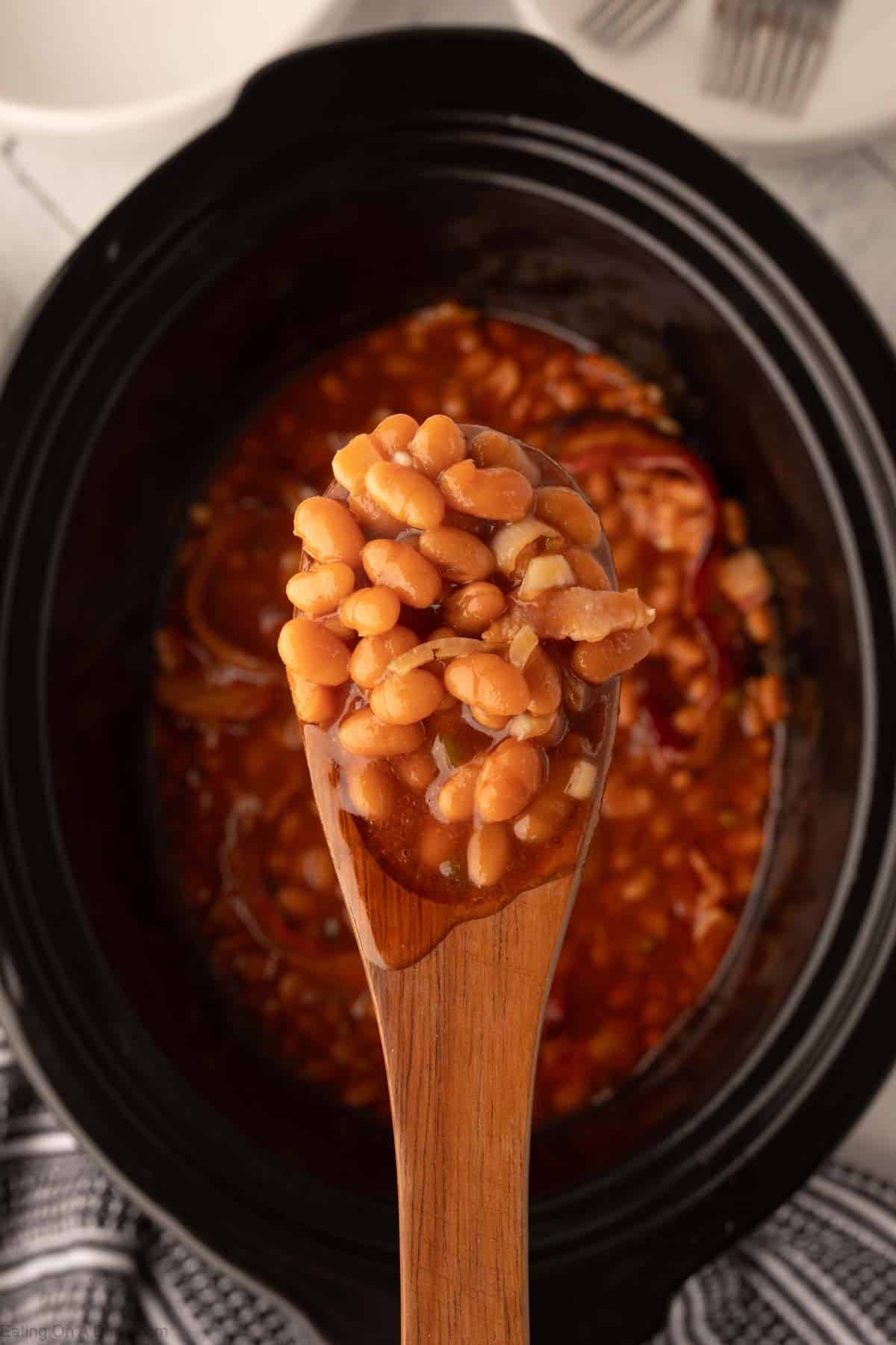 Pork and Beans in the slow cooker wiht a serving on a wooden spoon