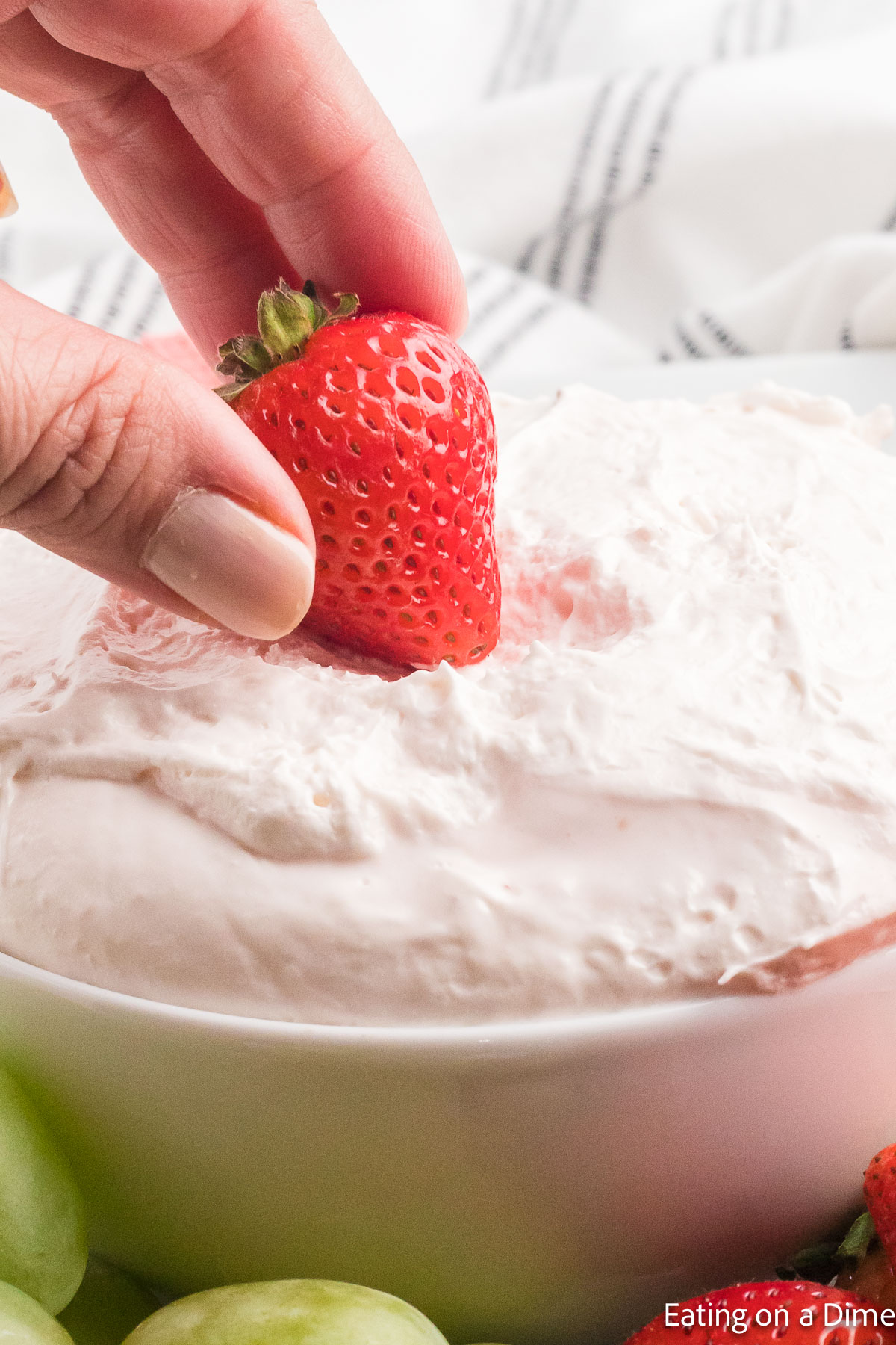 Dipping fresh strawberry in the fruit dip