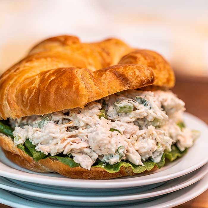 Close up image of chicken salad on a croissant on a plate. 