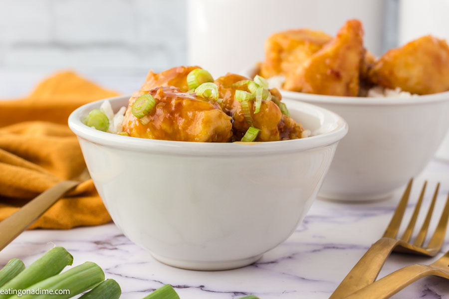 Close up image of orange chicken in a bowl with rice