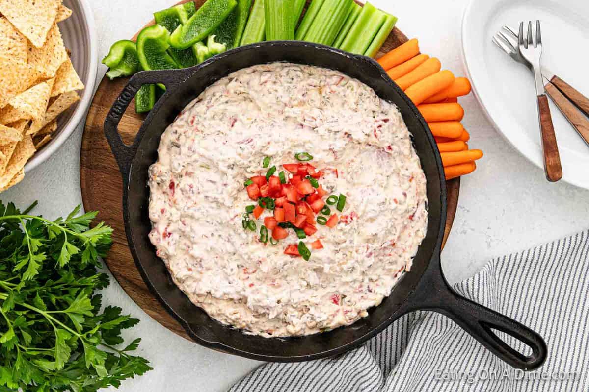 Sausage dip in a bowl with a platter of chips, carrots and celery