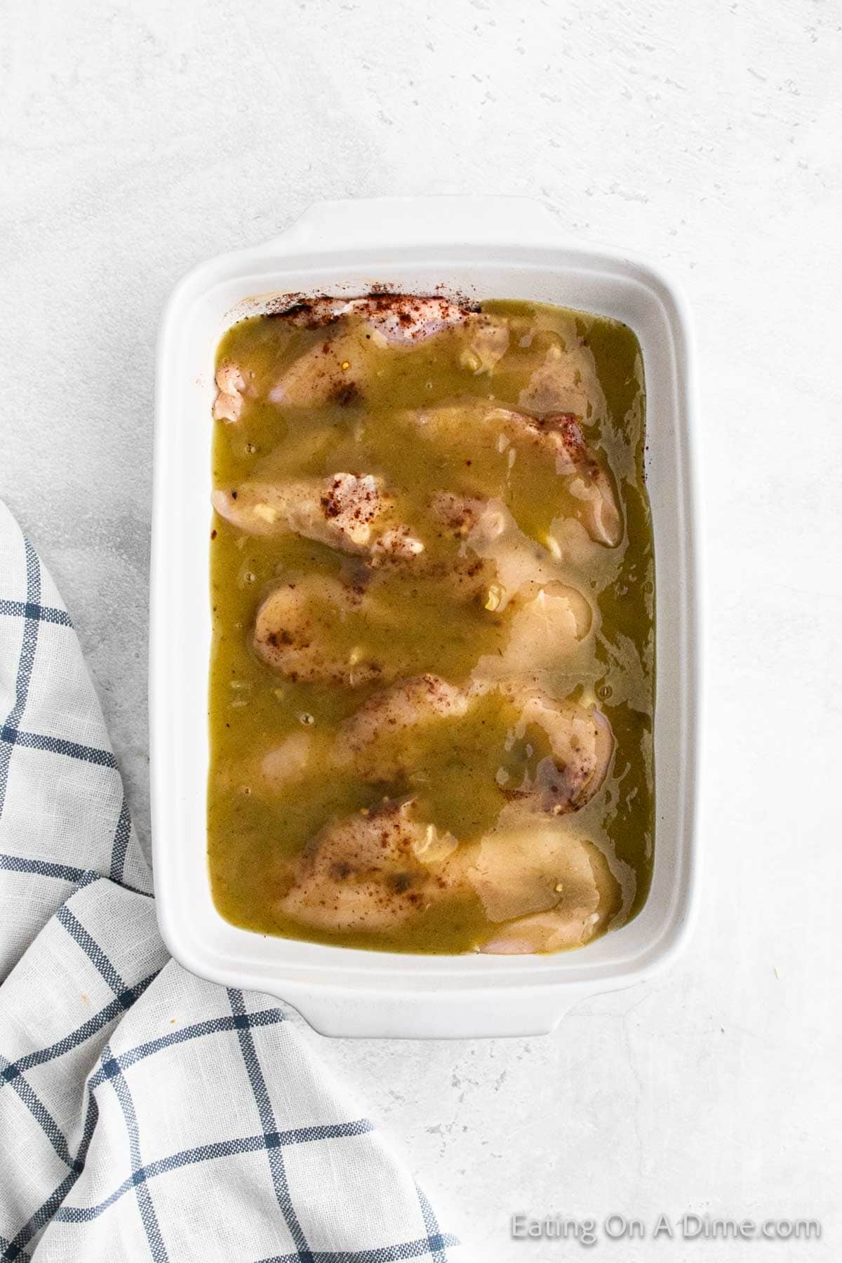 Chicken breast in a baking dish topped with chili powder and enchilada sauce
