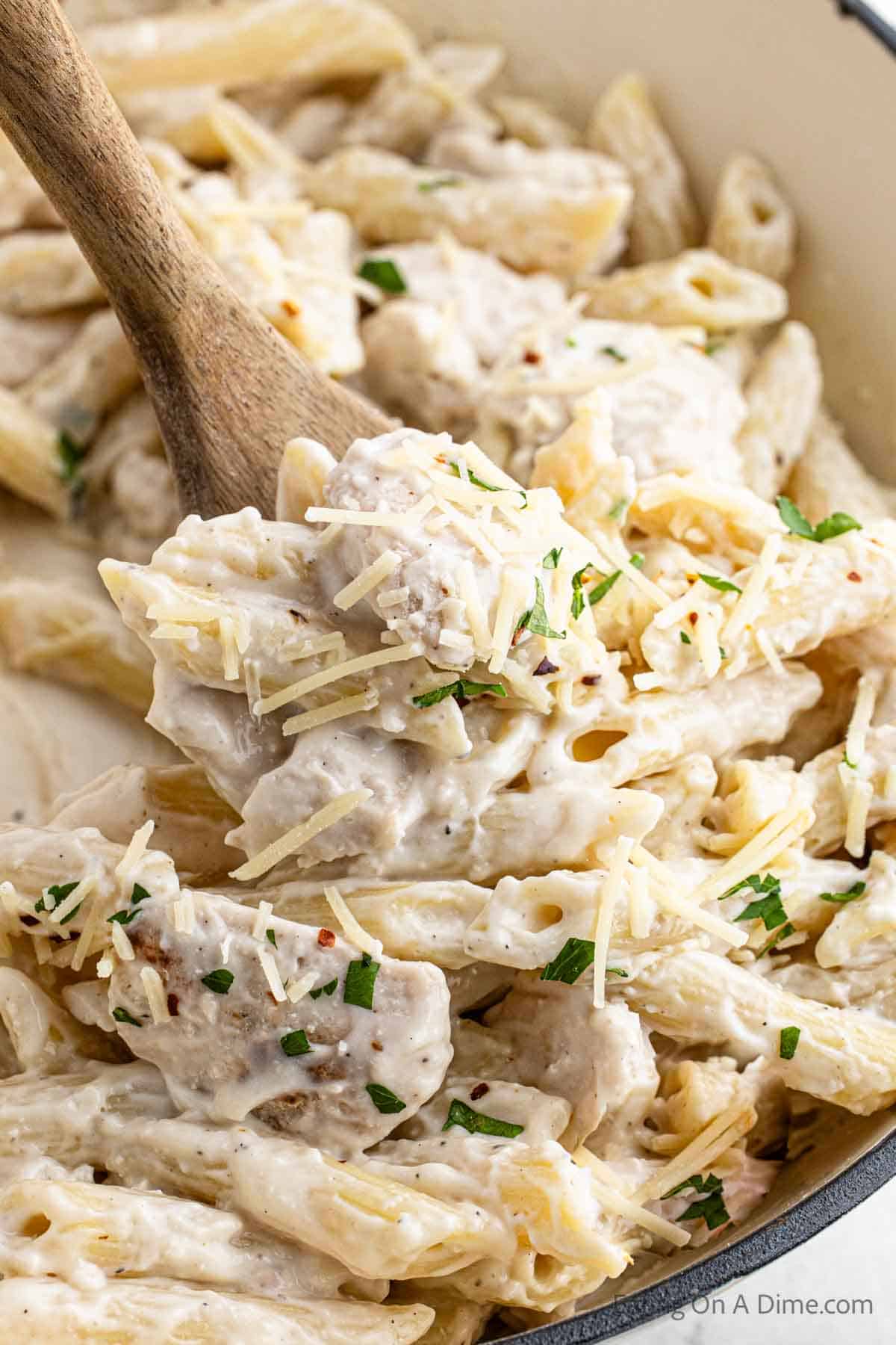 Close up image of chicken penne pasta on a wooden spoon
