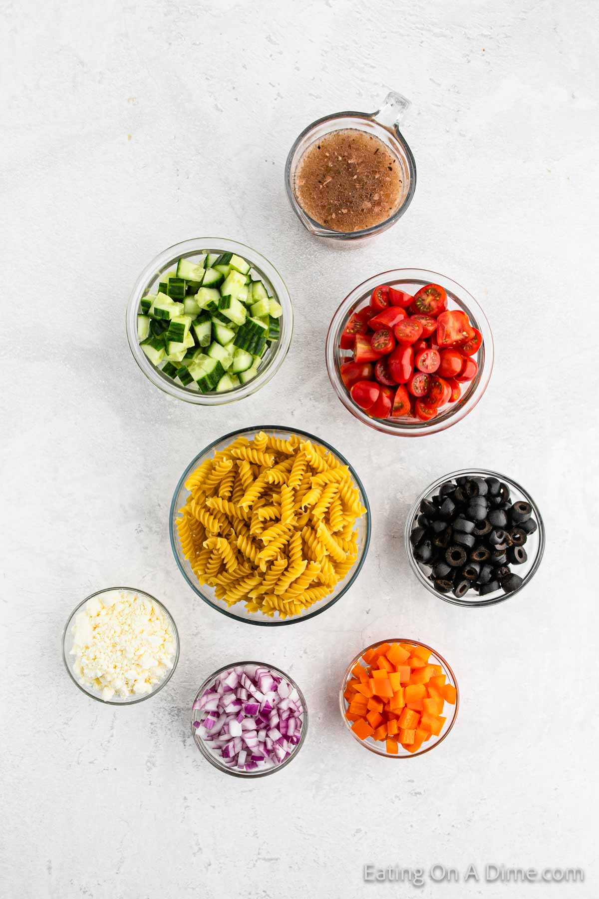 Greek Pasta Salad Ingredients - rotini pasta, english cucumbers, grape tomatoes, bell peppers, olives, feta cheese, red onion, greek vinaigrette dressing
