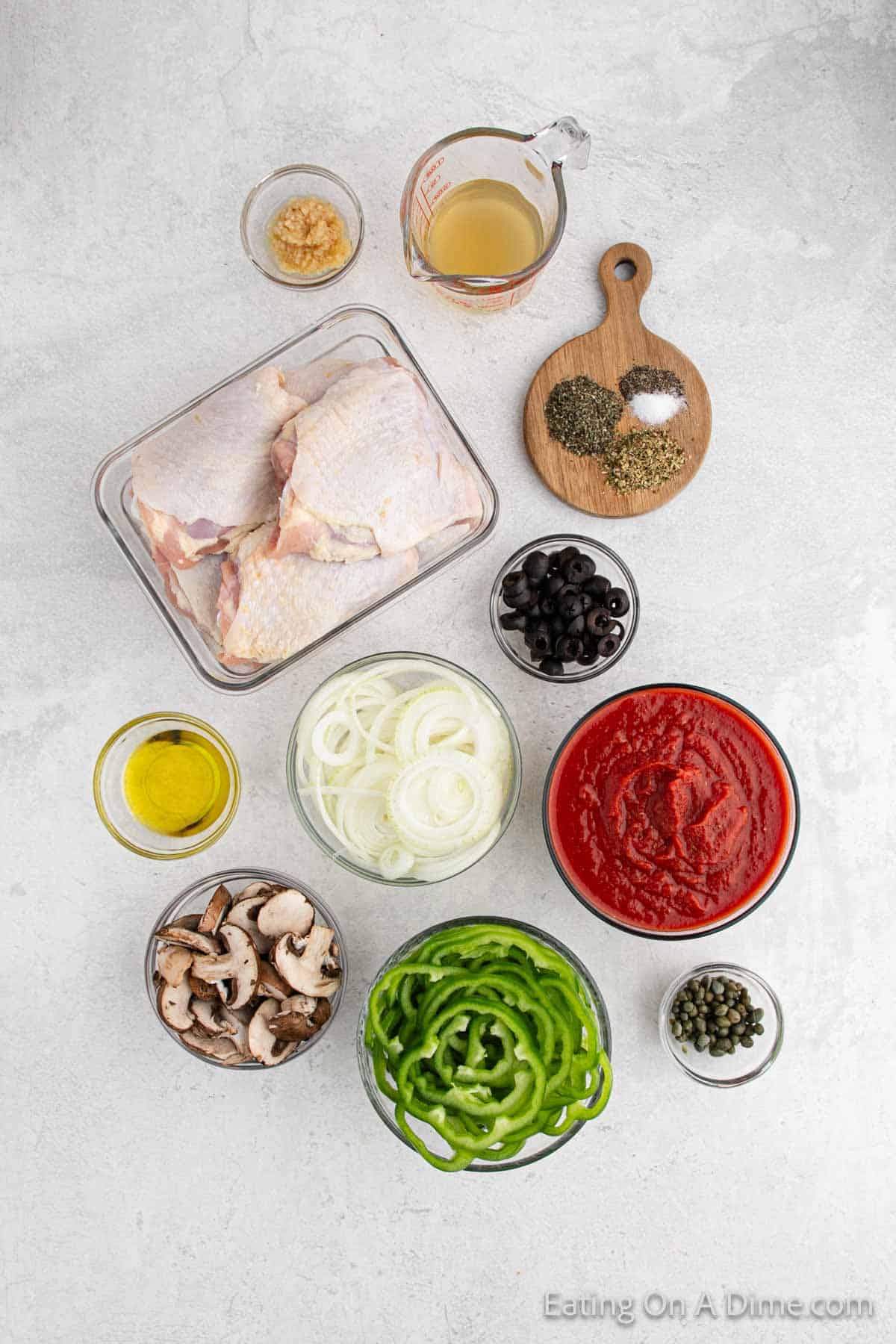 Chicken Cacciatore ingredients - chicken thighs, salt and pepper, olive oil, onion, bell peppers, garlic, mushrooms, crushed tomatoes, chicken broth, dried oregano, dried basil, black olives, capers, fresh parsley