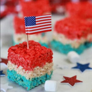 Red, white, and blue Rice Krispie Treats and topped with an American flag on top.