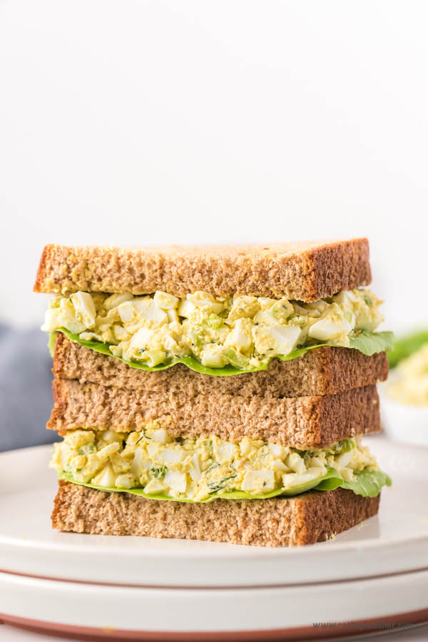 egg salad sandwich stacked on a white plate
