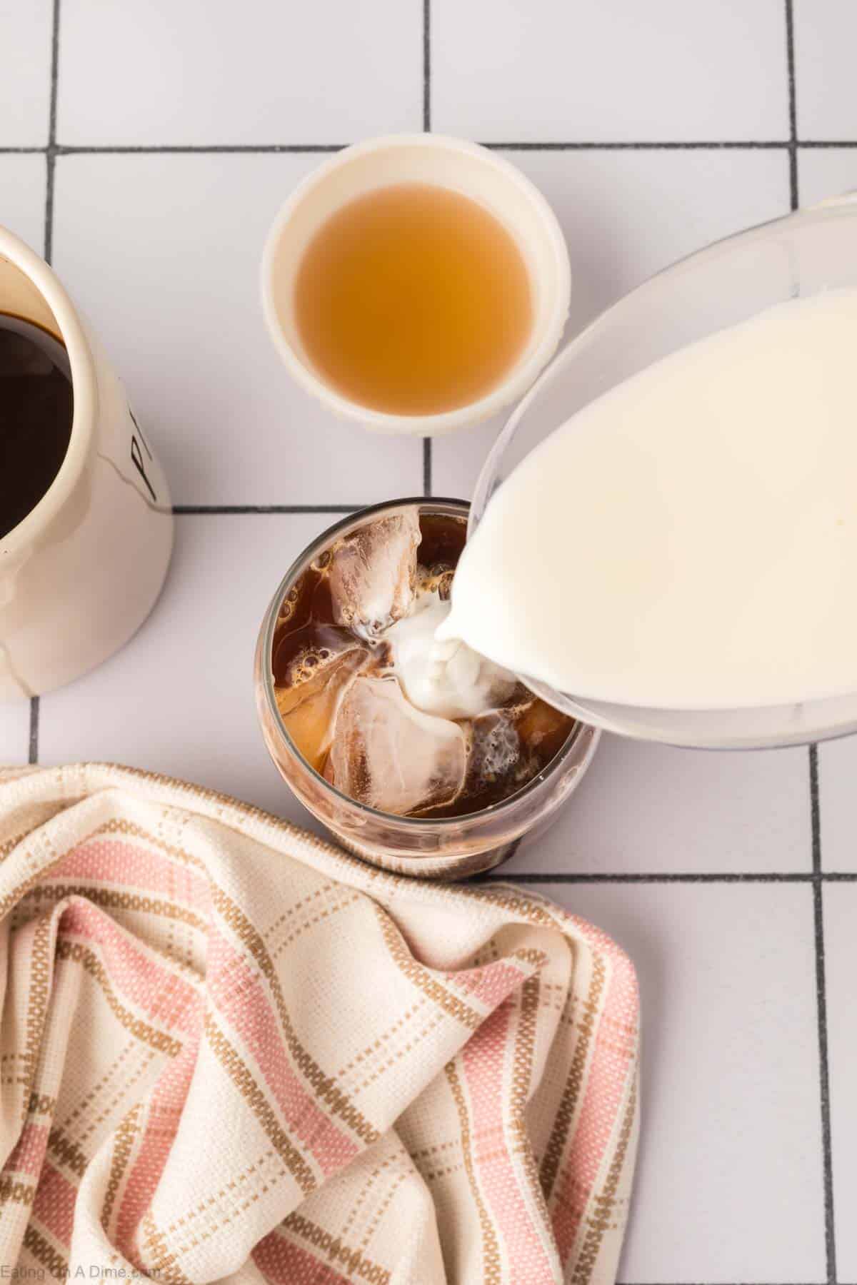 Pouring the milk into the glass of coffee