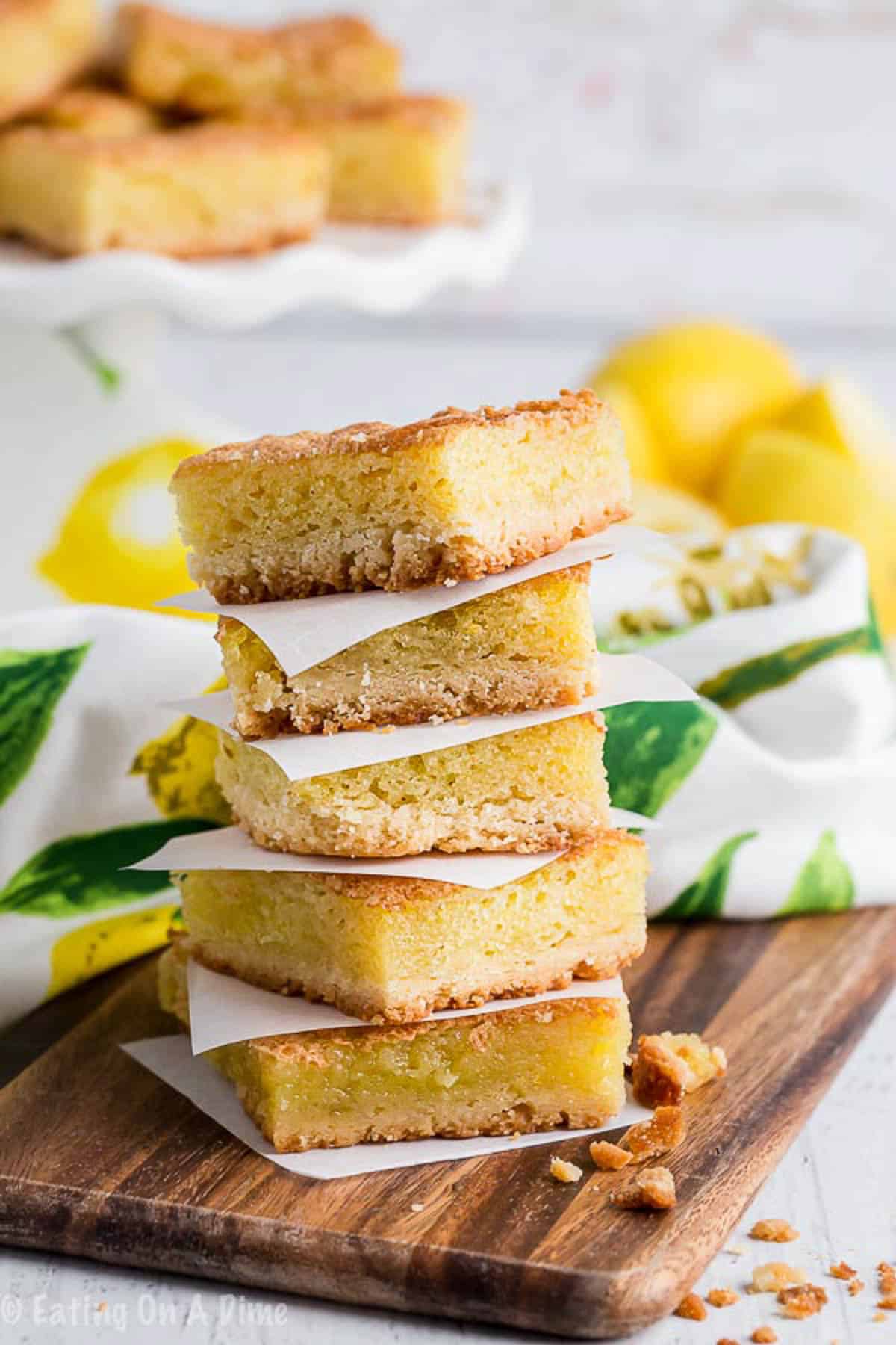 Lemon bars stacked on a cutting board
